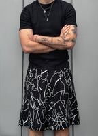 Person wearing a black t-shirt and black shorts with white abstract patterns against a gray background