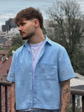 Man wearing a light blue shirt with a cityscape in the background