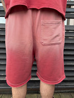 Person wearing pink shorts with a gradient effect against a metal fence background