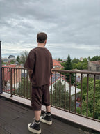 Person standing on a balcony overlooking a cityscape with a cloudy sky.