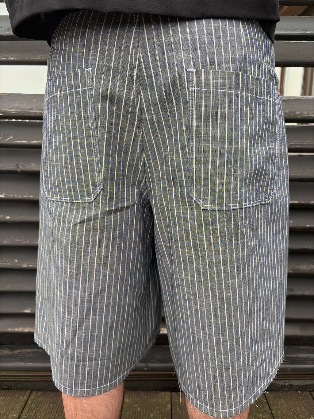 Person wearing gray pinstripe shorts with a blurred background