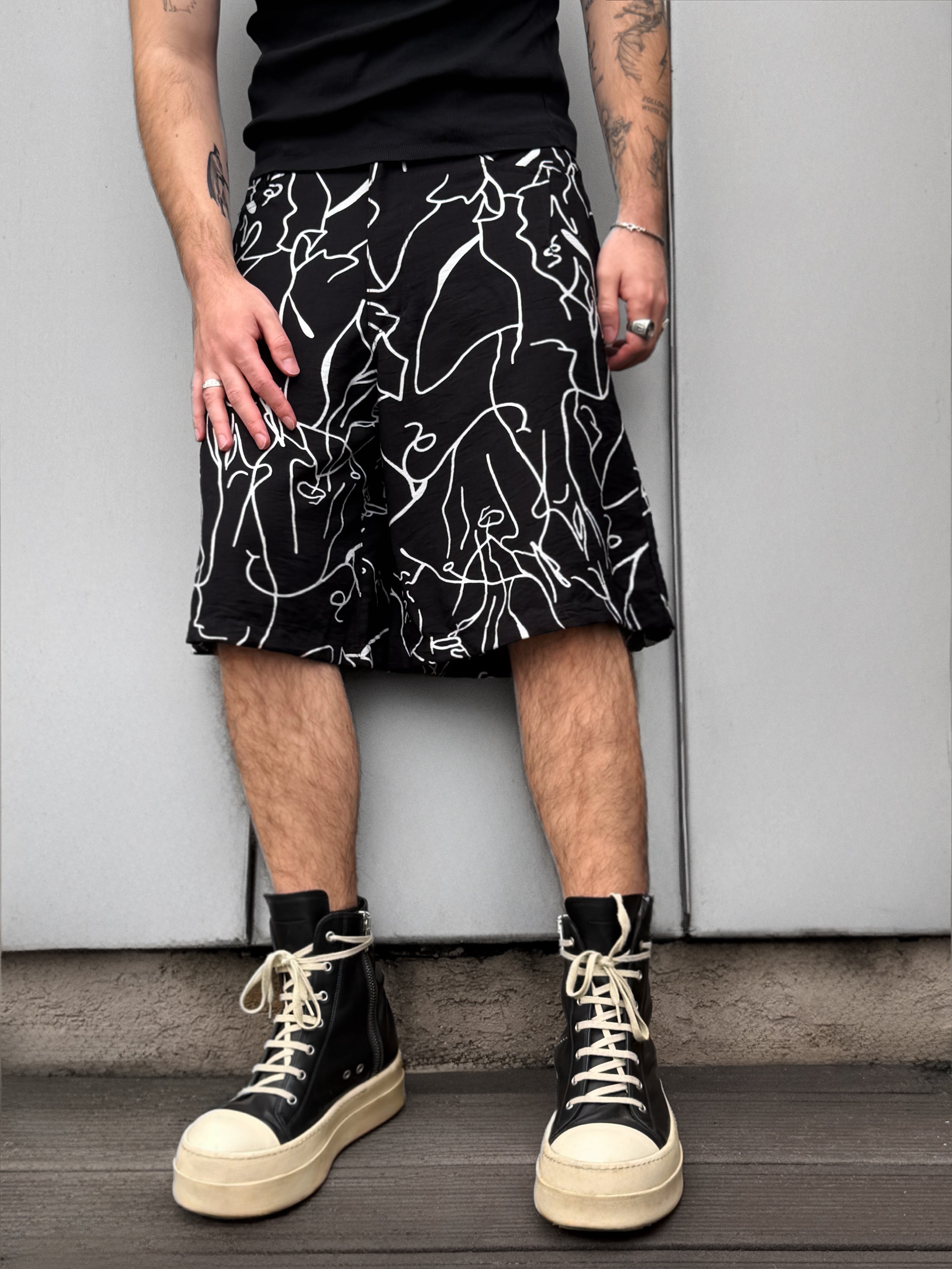 Person wearing a black and white patterned skirt with high-top sneakers against a plain background