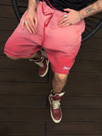 Person wearing pink shorts and red sneakers on a wooden floor