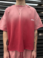 Person wearing a red distressed t-shirt with a logo against a wooden slat background