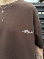 Brown sweatshirt with 'Skywear' logo on a person wearing necklaces.