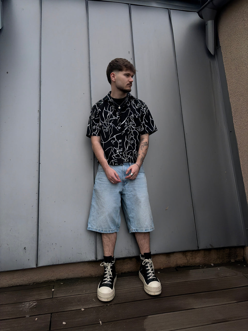 Person sitting on a gray surface with a wooden floor and wall in the background