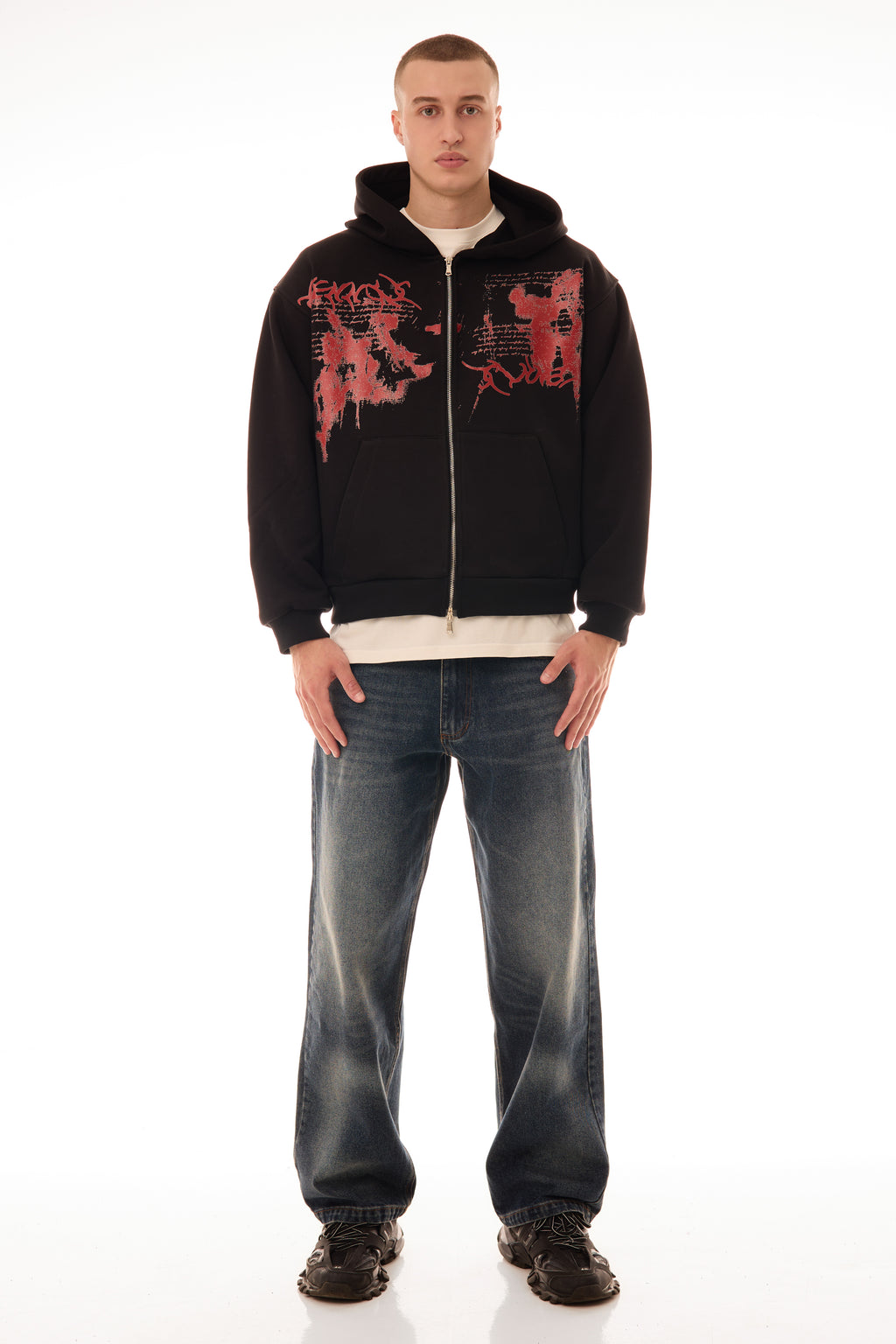 Model bărbat purtând Relic Black Hoodie, hanorac negru cu fermoar și print roșu pe față, stil streetwear oversized.