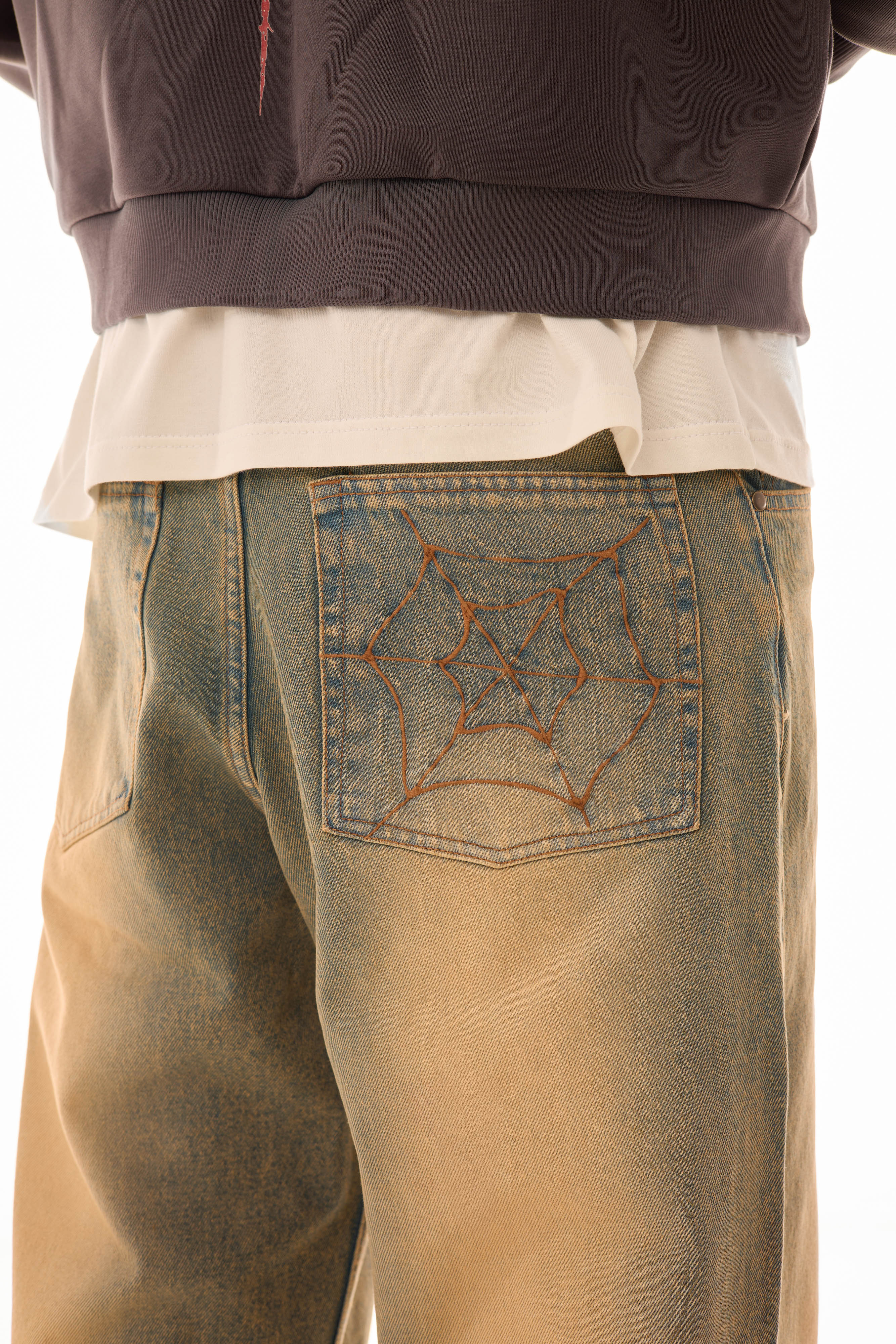 Detaliu buzunar spate al blugilor wide-leg albaștri cu efect stonewash și broderie model pânză de păianjen