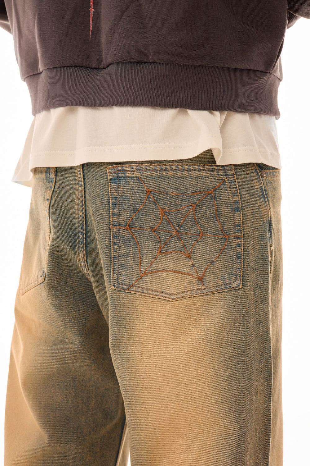 Detaliu buzunar spate al blugilor wide-leg albaștri cu efect stonewash și broderie model pânză de păianjen