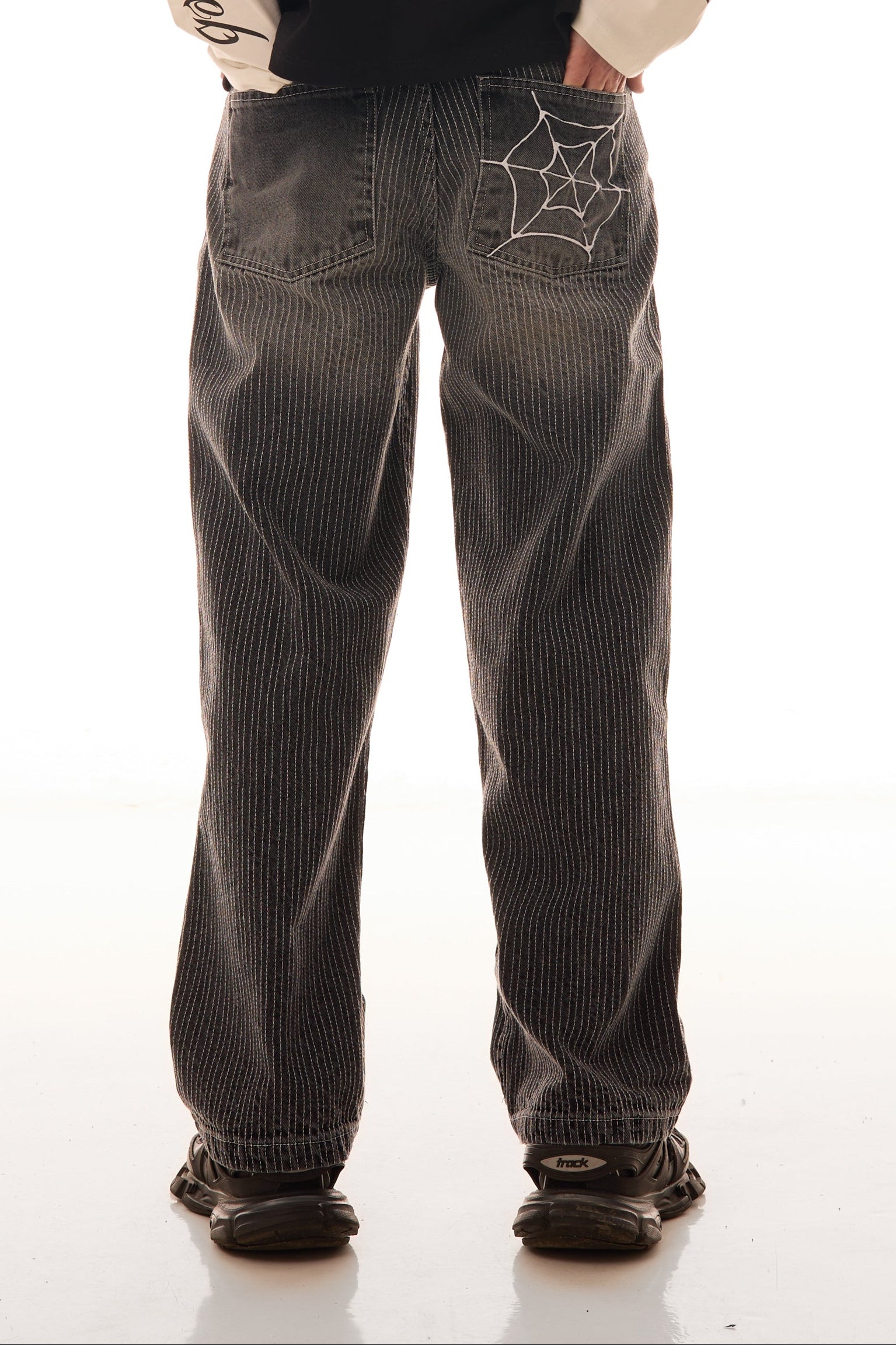 Close-up din spate cu blugii Axis Denim gri, wide fit, cu tighele verticale albe și broderie pe buzunarul spate.
