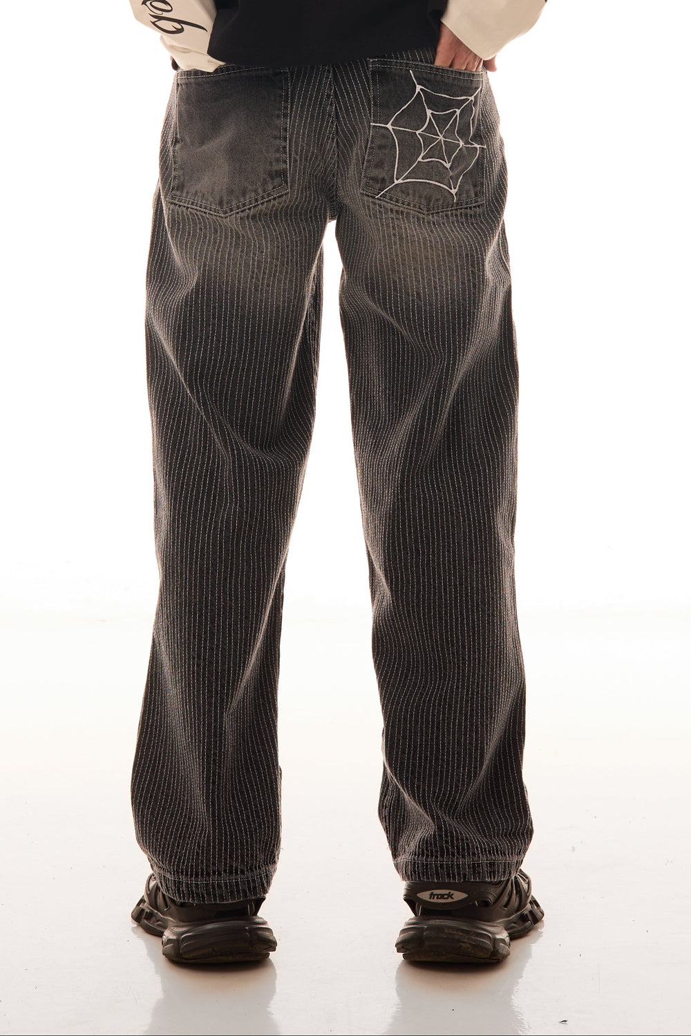 Close-up din spate cu blugii Axis Denim gri, wide fit, cu tighele verticale albe și broderie pe buzunarul spate.
