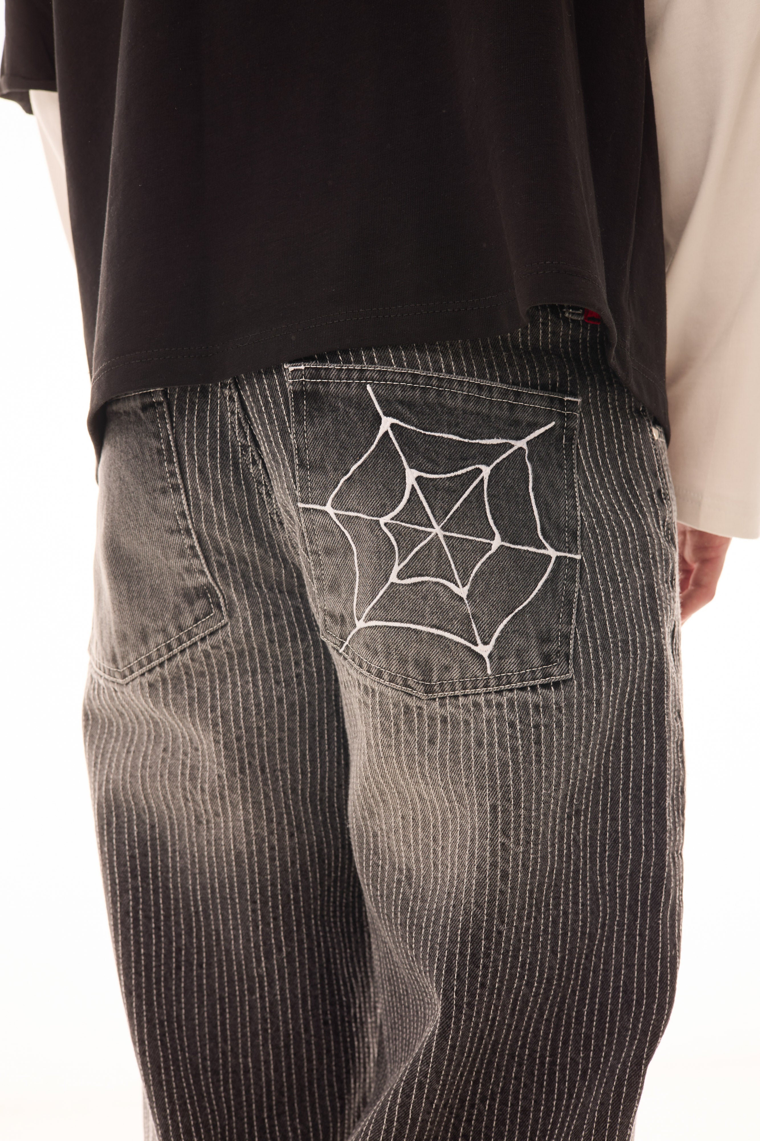 Detaliu buzunar spate la blugii Axis Denim gri, wide fit, cu tighele verticale albe și broderie tip pânză de păianjen.
