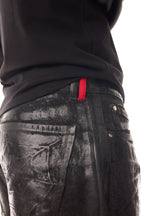 Detaliu close-up al blugilor Midnight Denim, cu coating cerat pe bază de silicon, buclă roșie la betelie și buzunar spate texturat.
