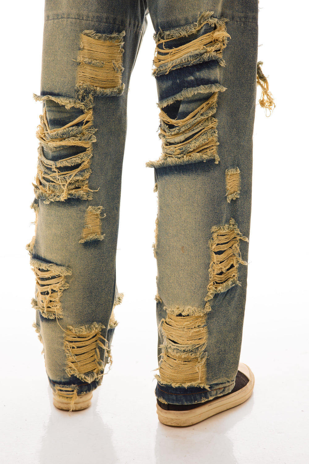 Close-up frontal cu blugii Shattered Denim Blue 13.5 OZ, wide fit, cu distressed heavy și rupturi foarte mari în partea de jos.
