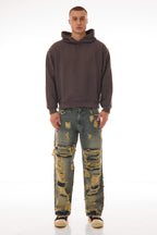 Model purtând blugii Shattered Denim Blue 13.5 OZ, wide fit, cu distressed heavy și rupturi mari pe partea frontală.
