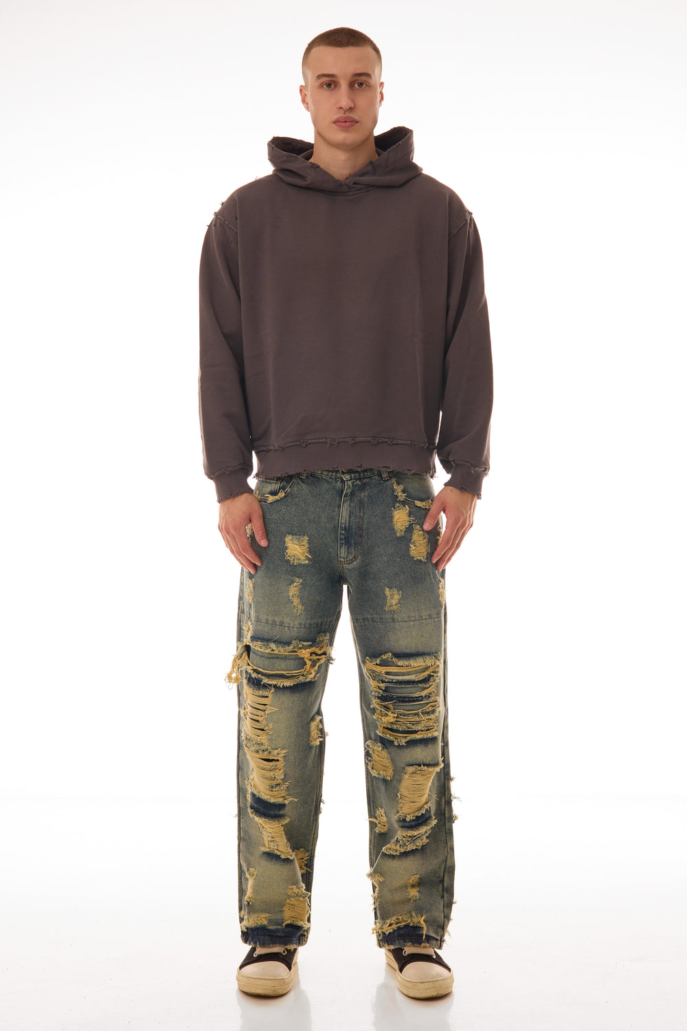 Model purtând blugii Shattered Denim Blue 13.5 OZ, wide fit, cu distressed heavy și rupturi mari pe partea frontală.
