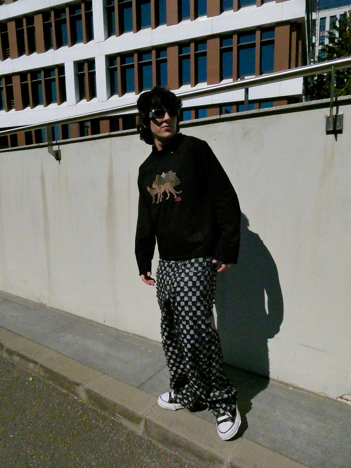 SKYWEB baggy black and white checkerboard denim jeans with frayed texture worn by a model in an urban setting