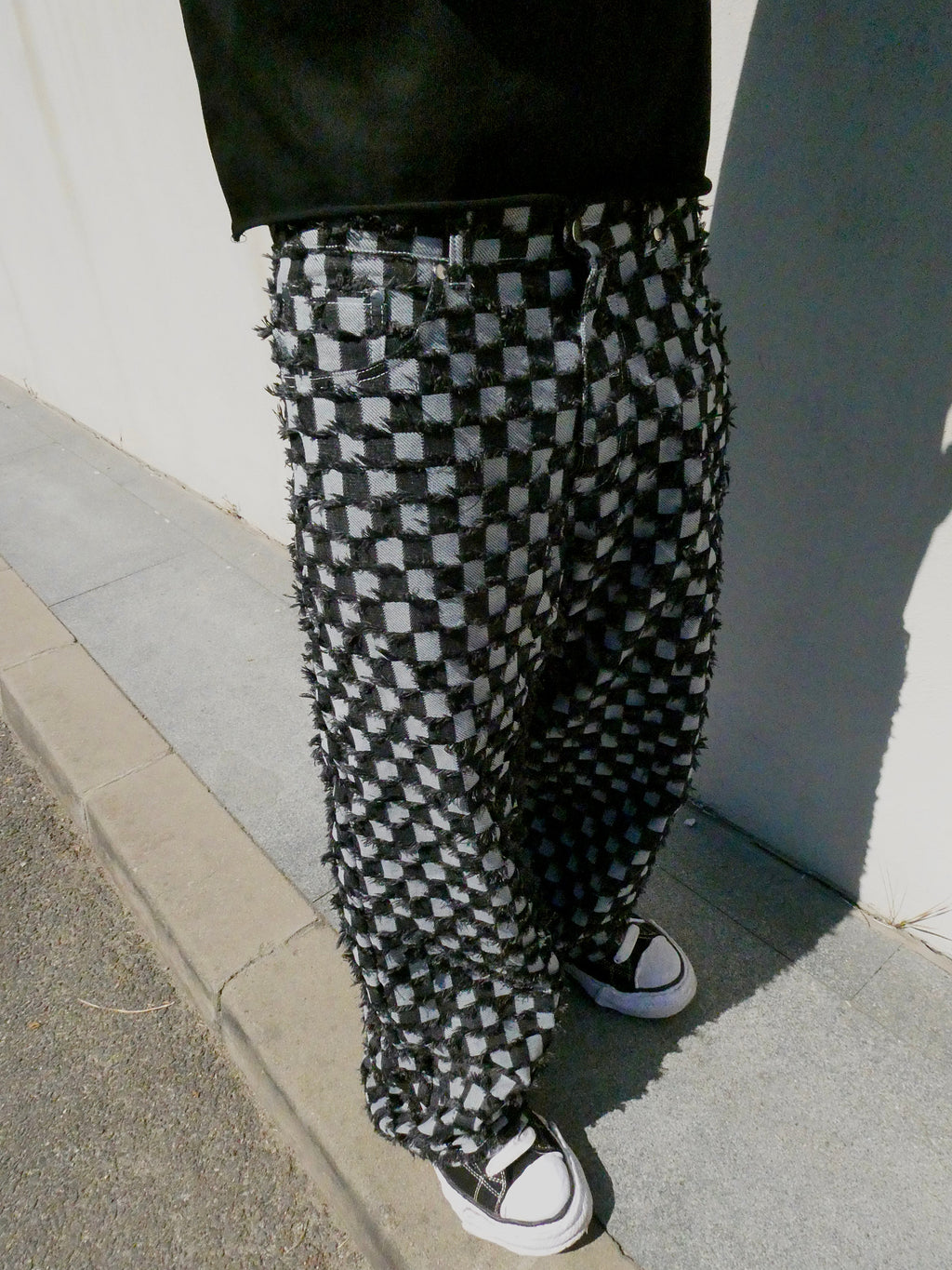 SKYWEB baggy black and white checkerboard denim jeans with raised frayed texture and a relaxed streetwear fit.