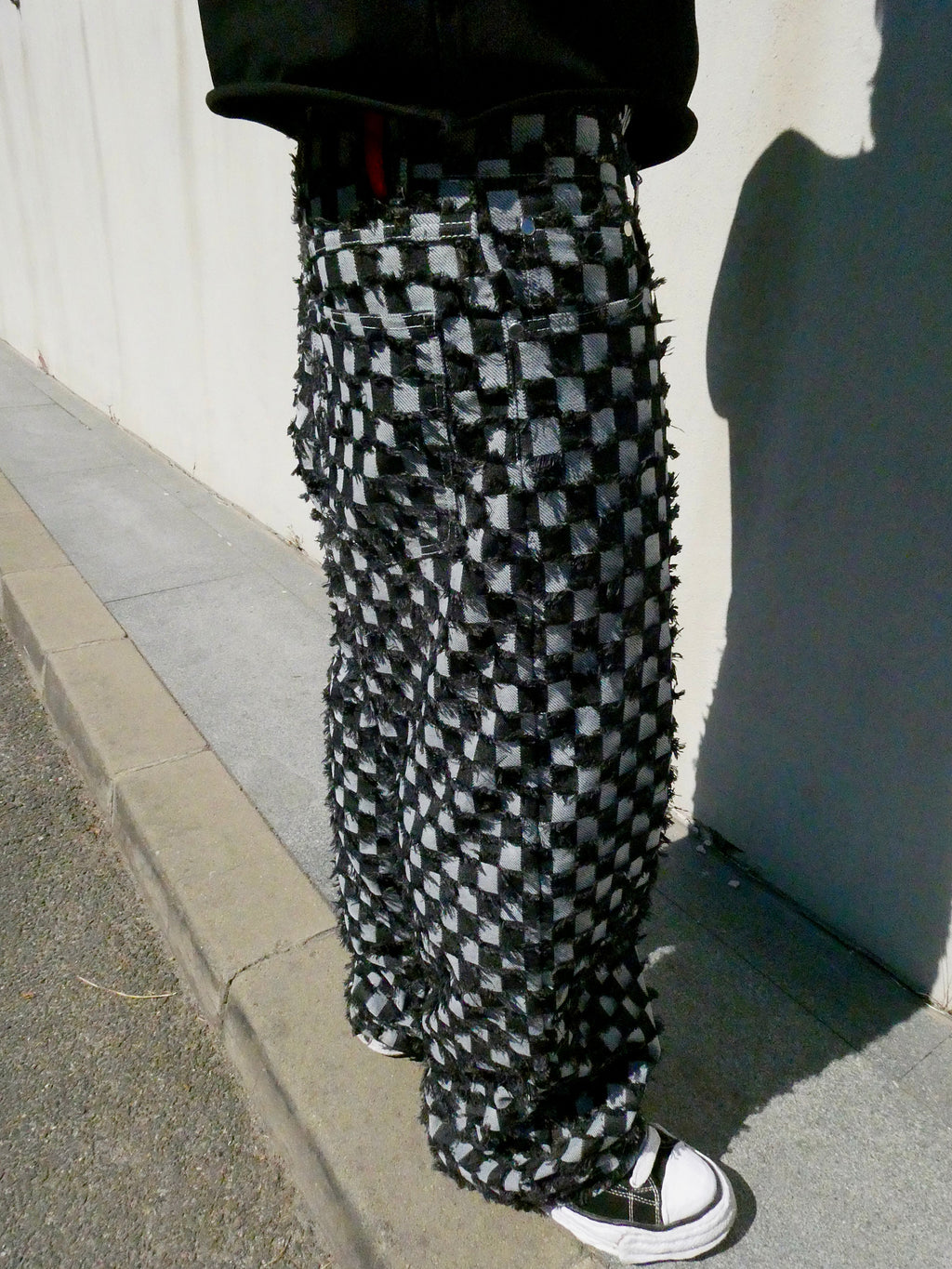 SKYWEB baggy black and white checkerboard denim jeans with raised frayed squares and a raw hem in a streetwear style.