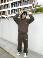 SKYWEB rust oversized hoodie with silver star studs, worn by a model in sunglasses standing against a modern building.