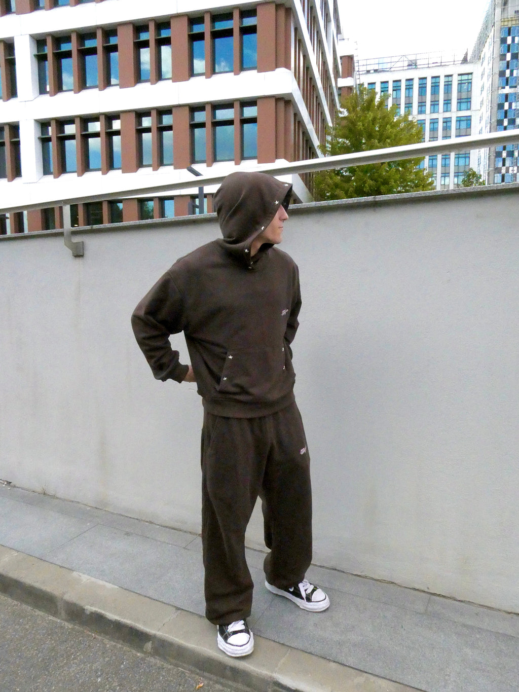 SKYWEB rust wide-leg cotton sweatpants with adjustable hems and embroidered logo worn by a model in an urban setting.