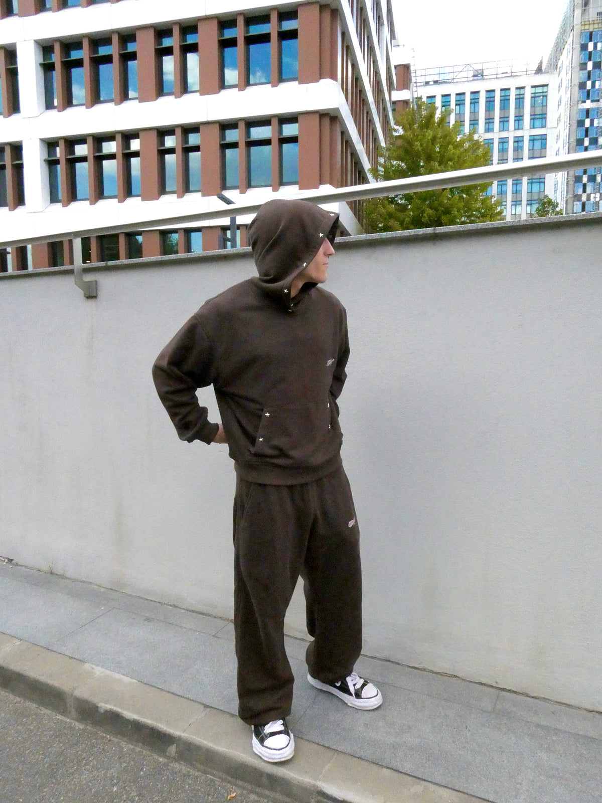SKYWEB rust wide-leg cotton sweatpants with adjustable hems and embroidered logo worn by a model in an urban setting.